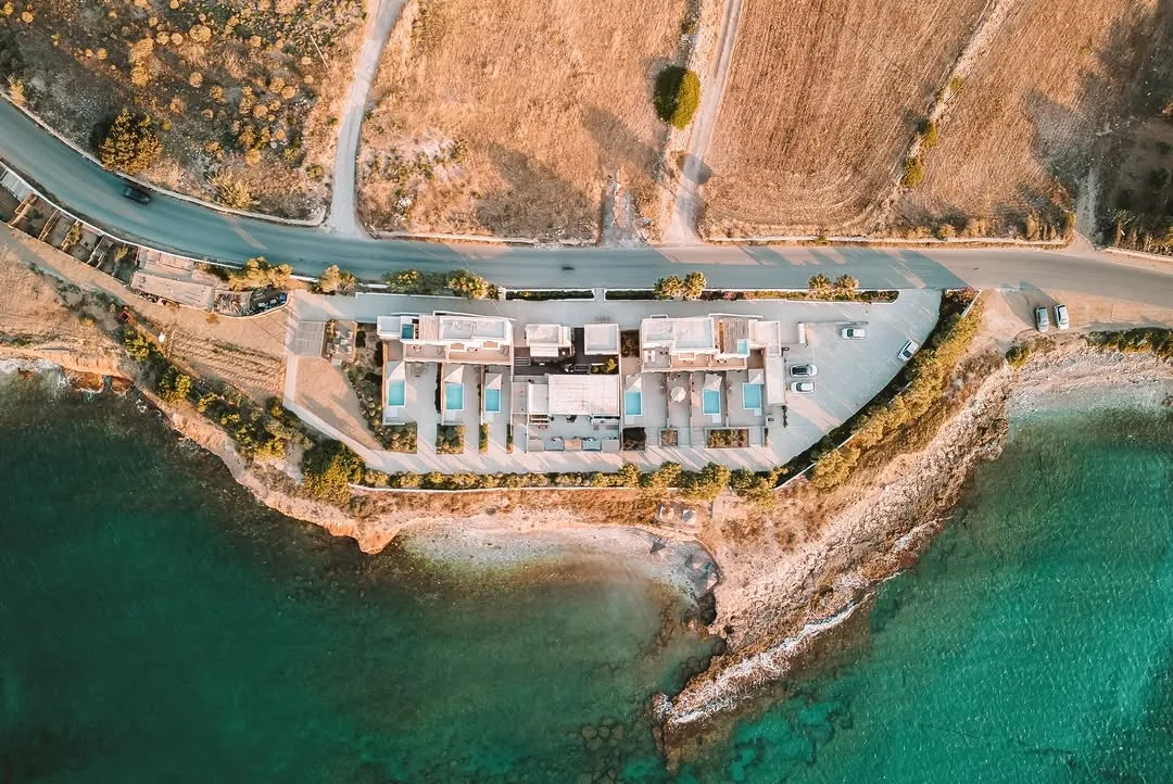 Aerial view of Paros Comfy Suites on the Xifara peninsula near Naoussa, surrounded by turquoise water