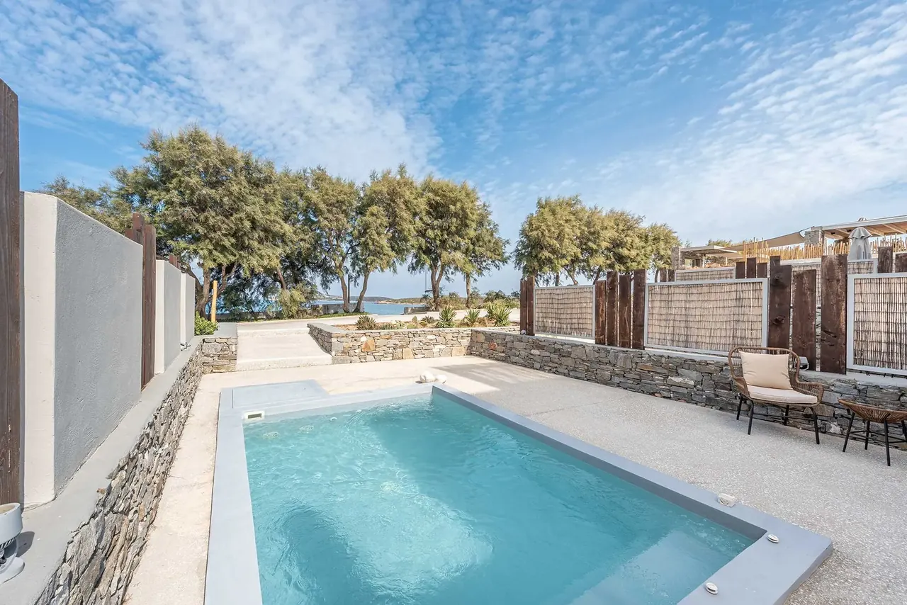 Private pool in the courtyard of a ground-floor suite at Paros Comfy Suites, with trees and sea beyond